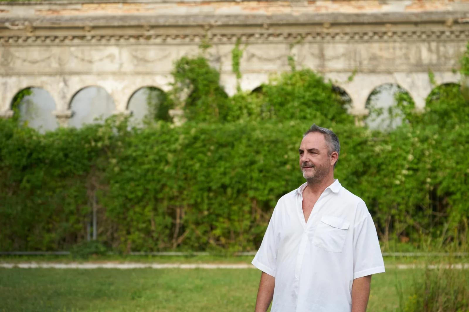 Fabio Semenzato davanti a un antico porticato ad archi coperto di verde