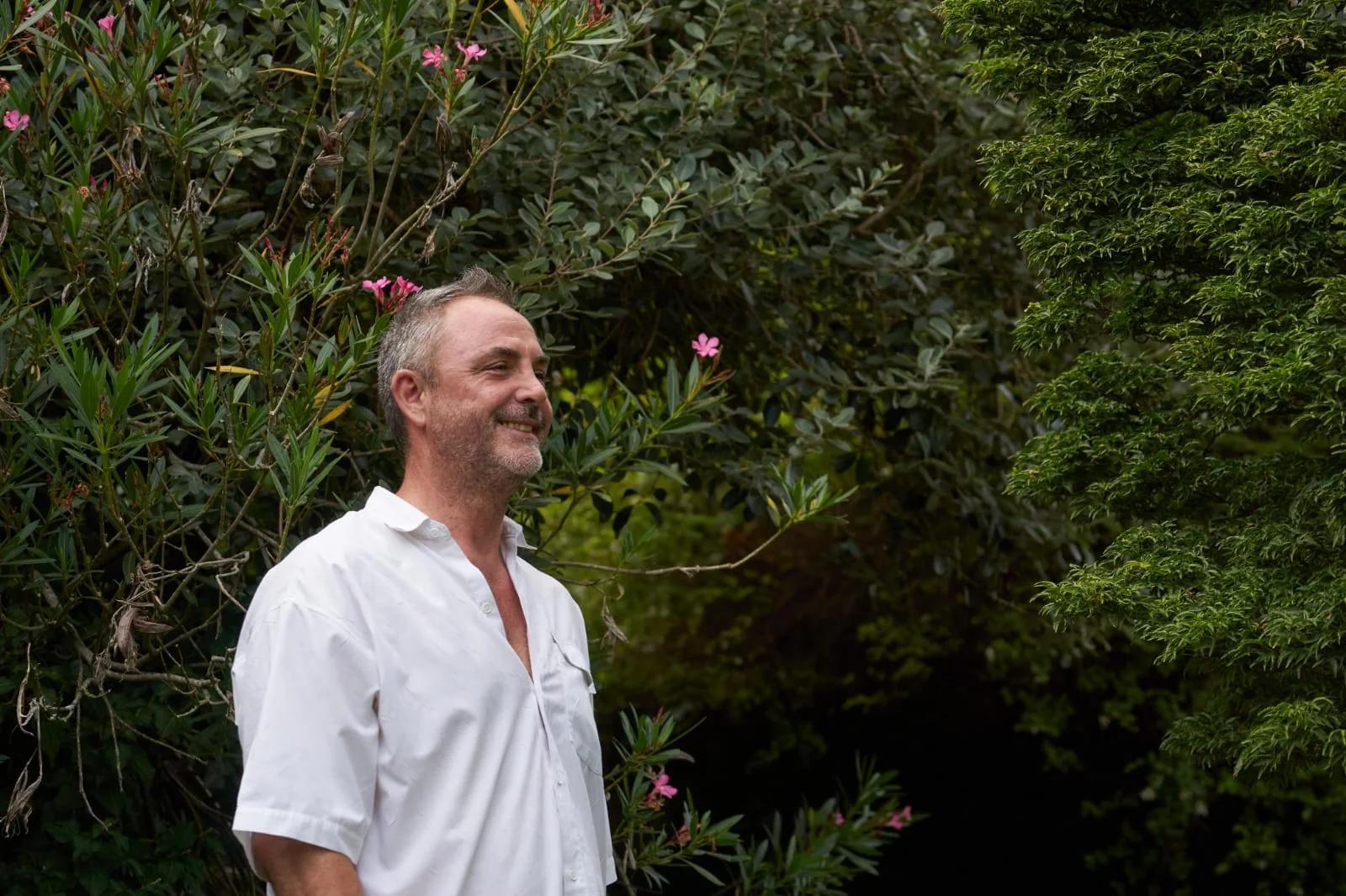 Fabio Semenzato sorridente in un giardino, tra oleandri in fiore